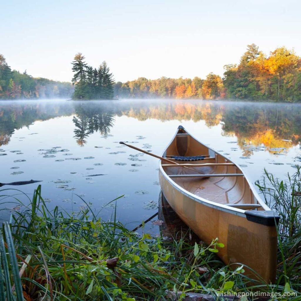 A boat on calm lake at sunrise - Nature Images