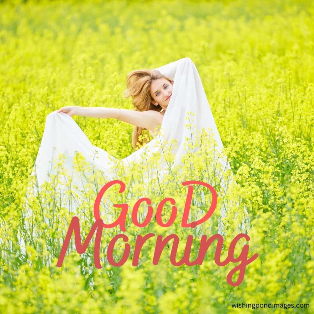 A young girl wearing a long white dress posing for a dance standing in the yellow flowers field in the morning