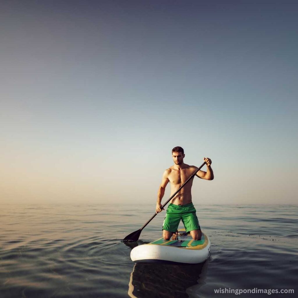 A young man on a paddle board floating in the lake - Nature Images