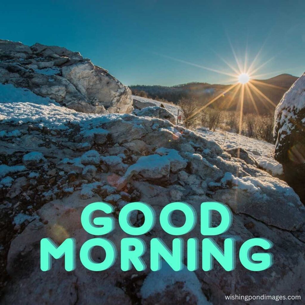 The sun's rays fall on the big rocky mountains covered with ice in the morning