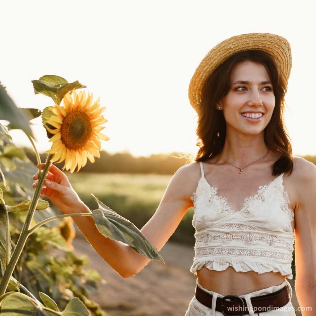 Young girl smiling and holding the sunflower in the field - Nature Images