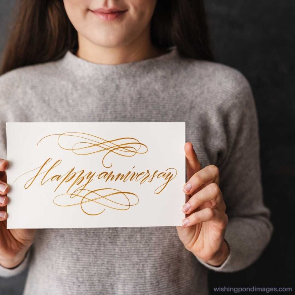 Pleased caucasian girl showing happy anniversary card at camera indoors