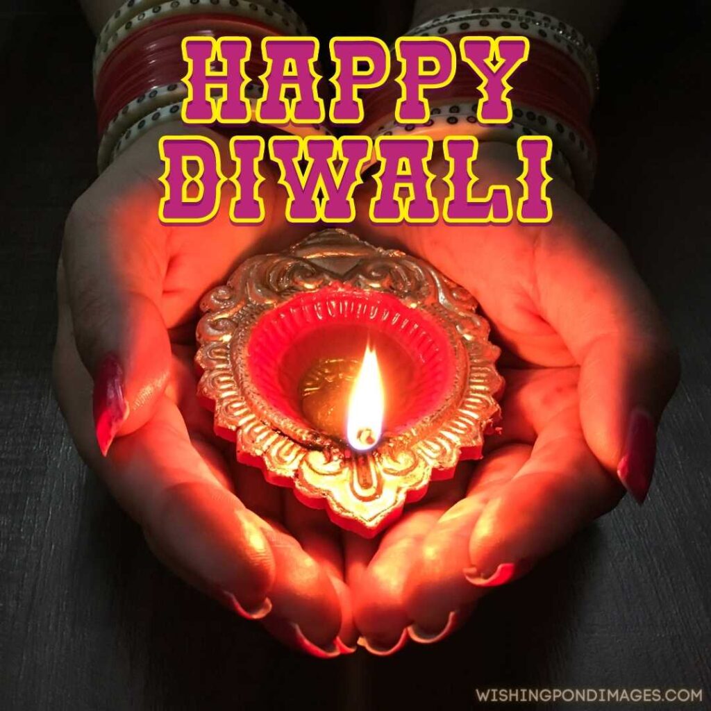 A woman holding fire lamp diya in her hands - Happy Diwali Images