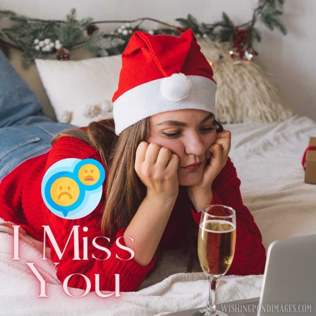 A sad young woman lying on the bed in the bedroom wearing a Christmas hat watching a laptop 