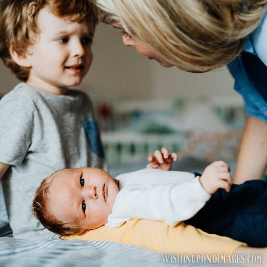 A beautiful young mother with a newborn baby and his toddler brother at home, talking. Newborn baby images