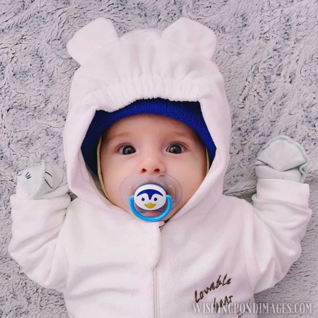 A newborn baby in full body cover suit dummy in mouth. Newborn baby image