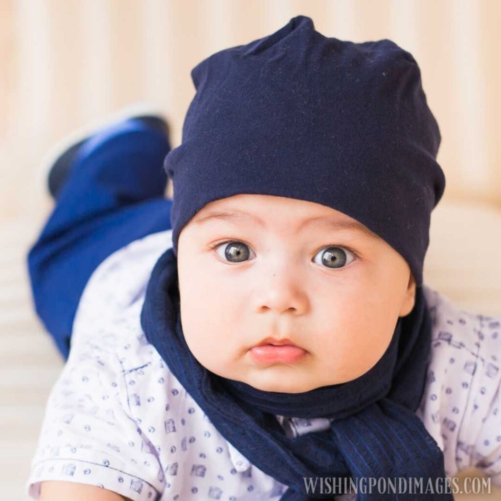 A portrait of a cute newborn baby in a white like a bear cub hat lying on its stomach. Newborn baby images (2)