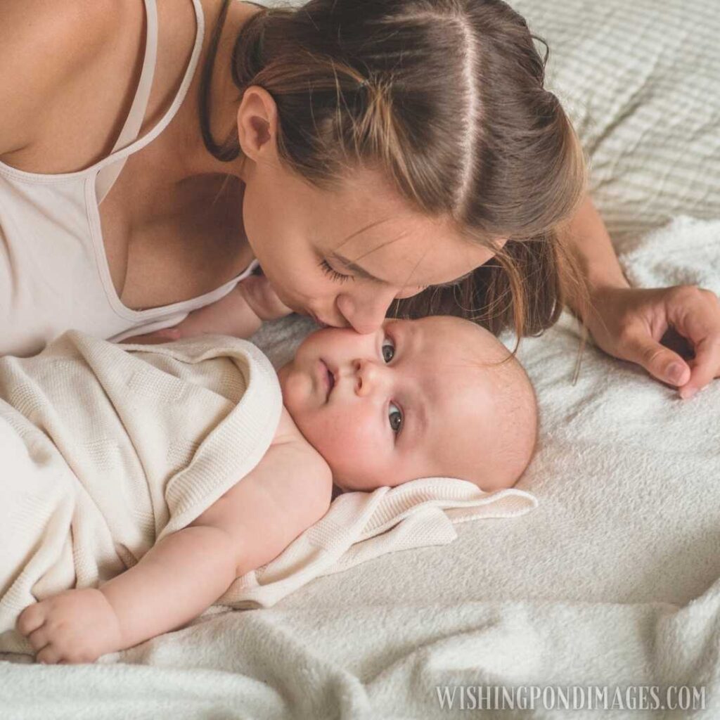 A young mother lying with her newborn baby and kissing. Newborn baby images