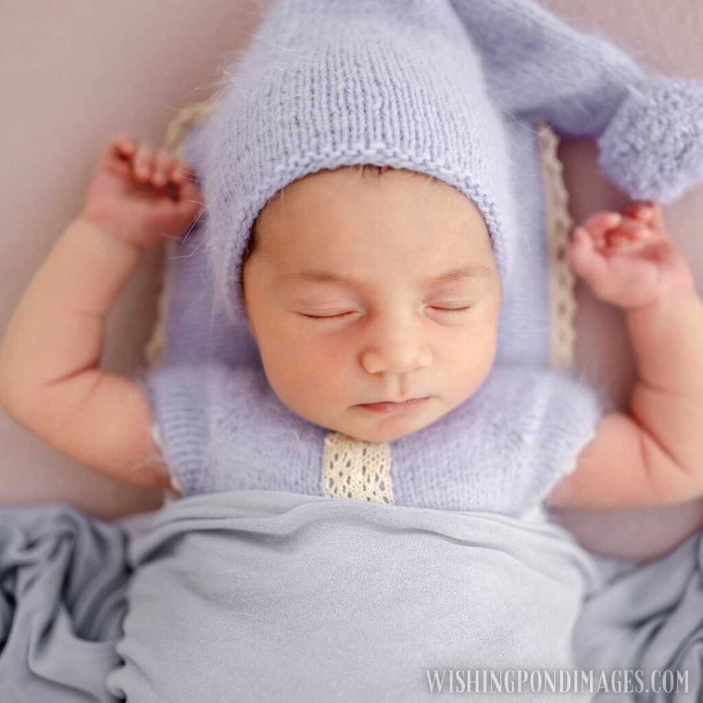Beautiful little newborn baby girl wearing knitted costume and hat sleeping with hands up under blanket. Newborn baby images