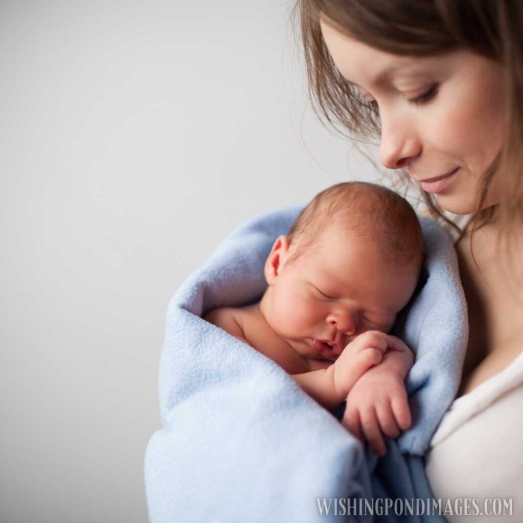 Close up of beautiful young woman holding adorable baby wrapped in blue blanket. Newborn baby image