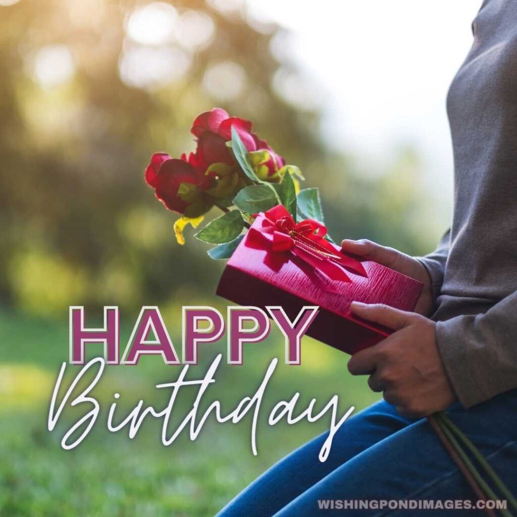 Closeup image of a woman holding red roses flower and a gift box in the park - Happy Birthday Flower Images