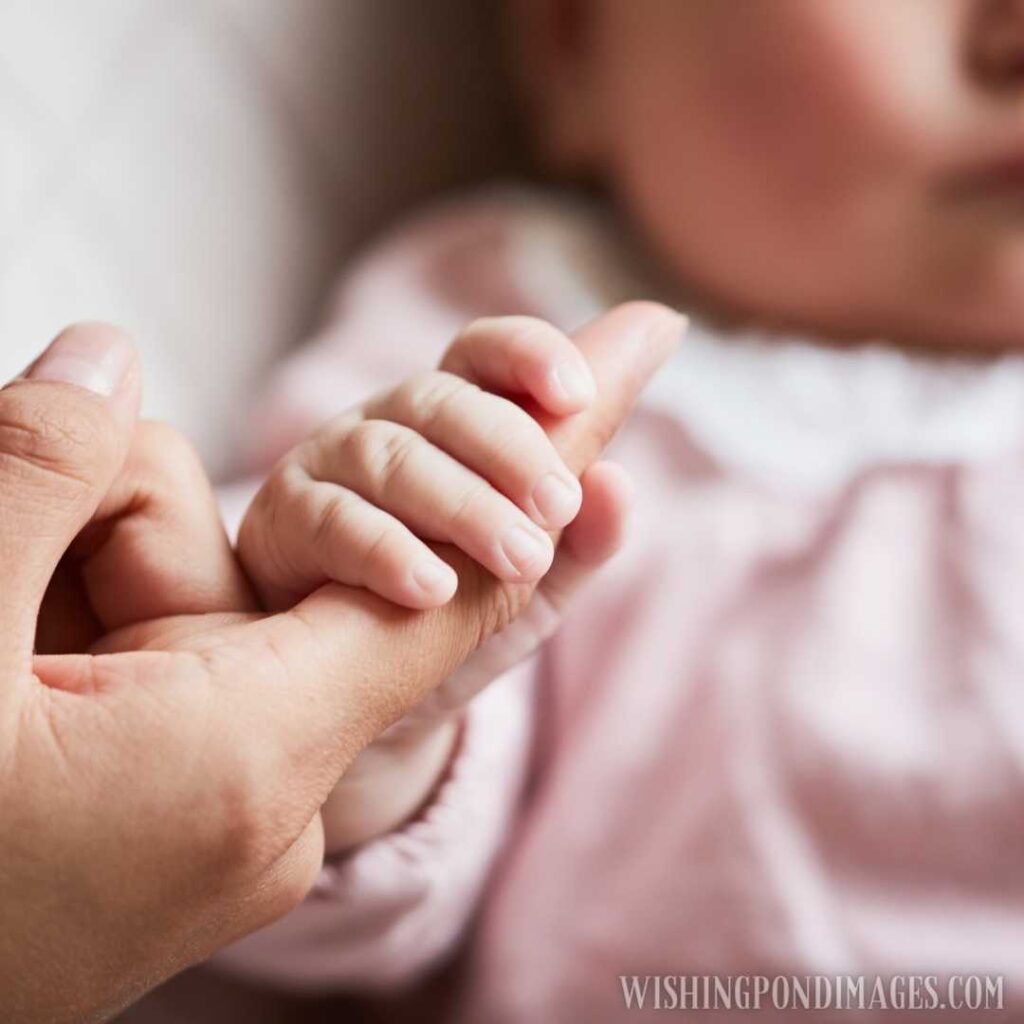 Closeup of newborn baby holding hand of her mother. Newborn baby image