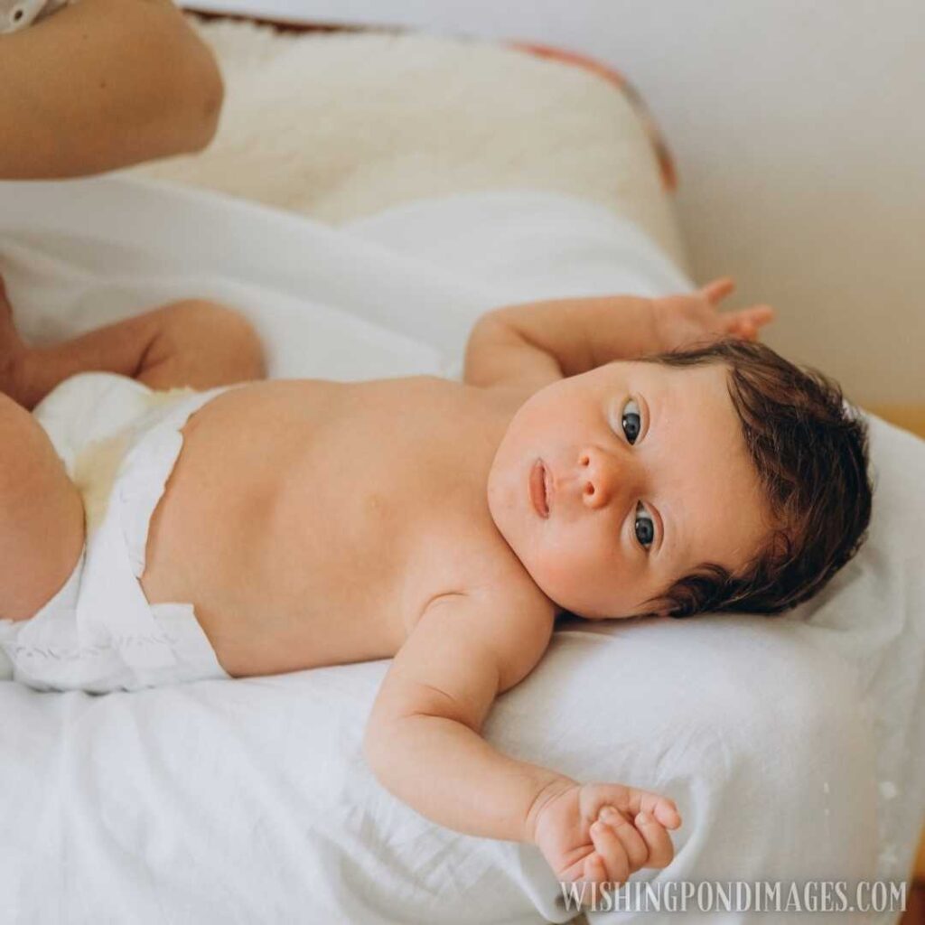 Cute little newborn baby wearing nappy and lying on the be at home. Newborn baby images