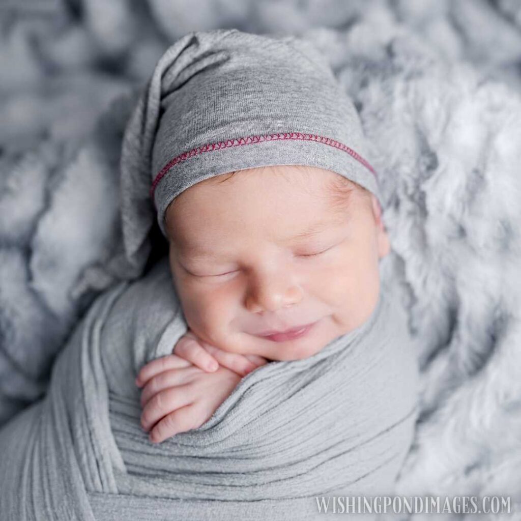 Cute newborn baby boy swaddled in grey fabric sleeping on fur blanket. Newborn baby images