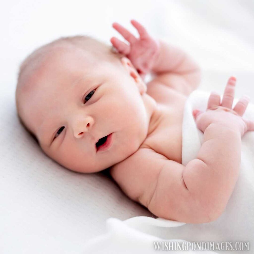 Cute newborn baby girl lying in the bed and falling asleep holding her hands close to head. Newborn baby images