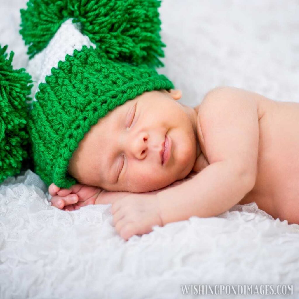 Newborn baby boy sleeping on bed wearing green-colored winter cap. Newborn baby images
