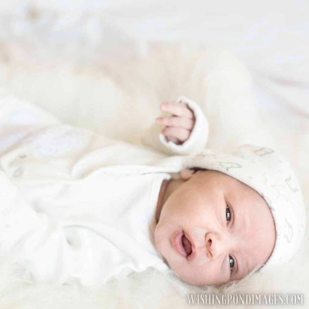 Newborn baby wearing white costume lying on bed at home. Newborn baby images