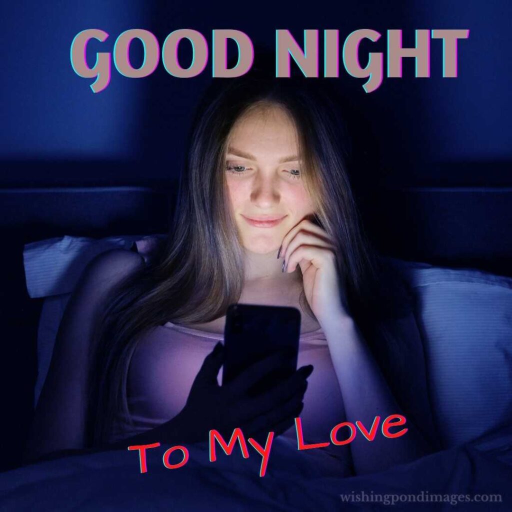 Young beautiful woman at night sitting in bed with smartphone