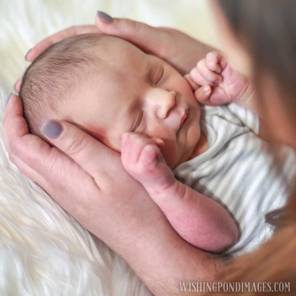 Young woman holding new baby gazing at his sleeping face. Newborn baby image