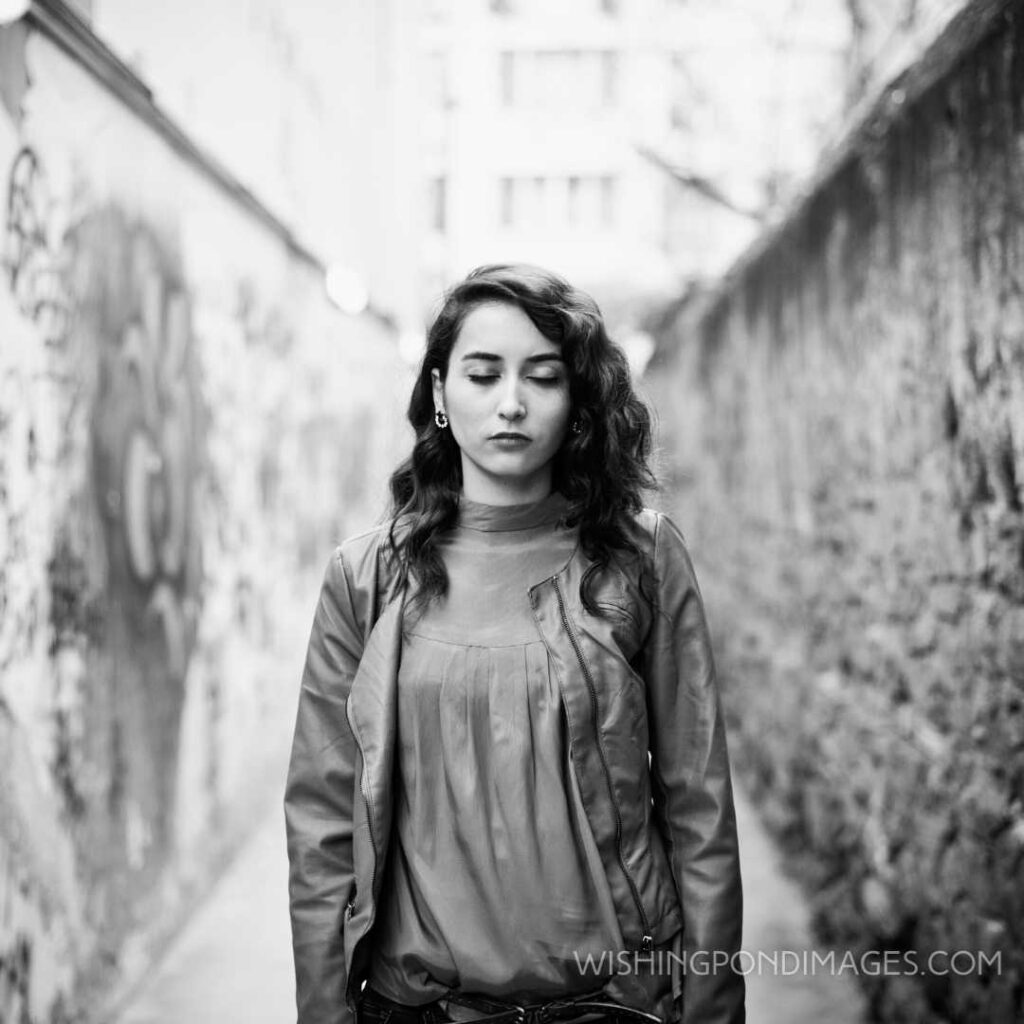 A young alone woman closing her eyes in the backstreet. Feeling alone images girl.