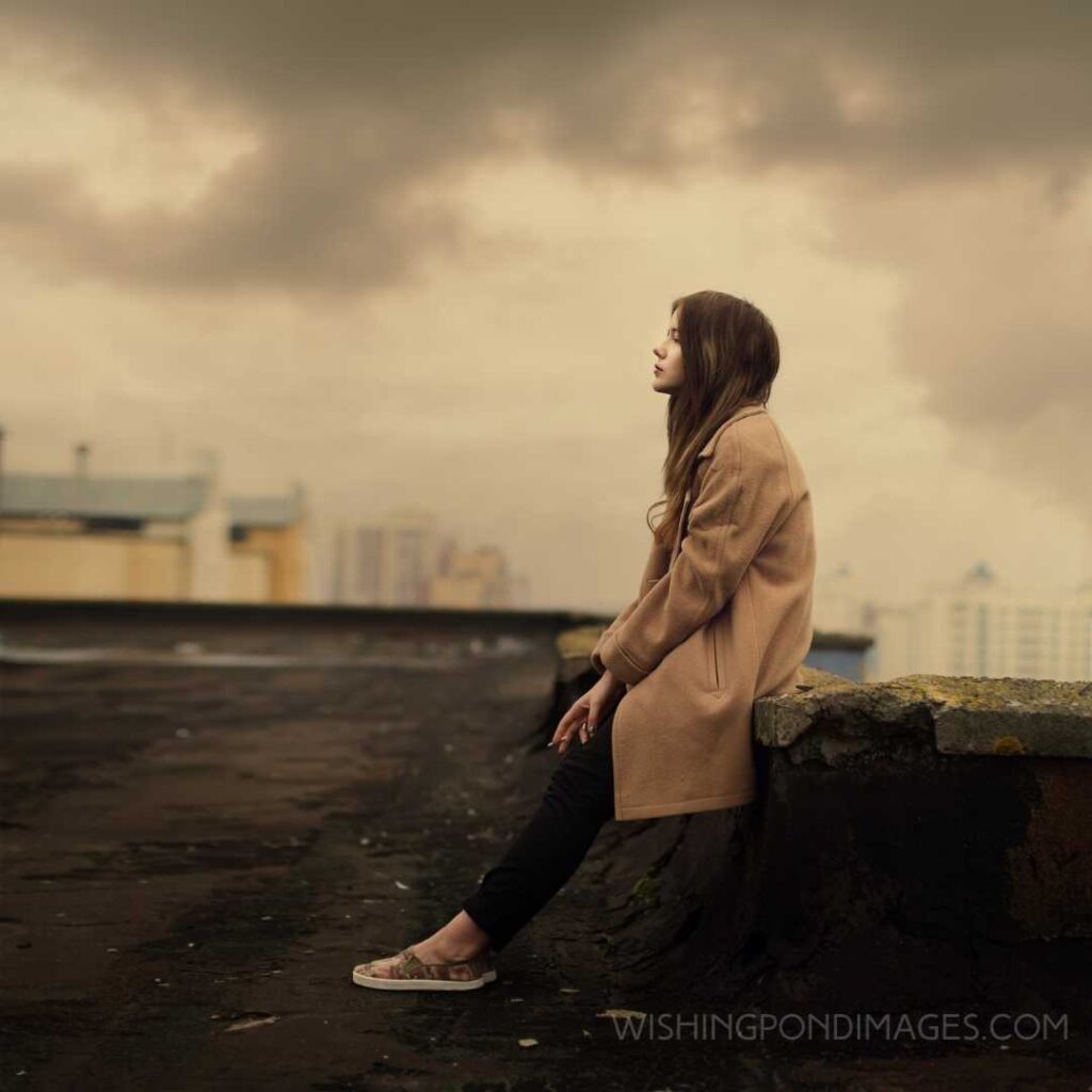 A young girl sitting alone on top of the old building. Feeling alone images girl.