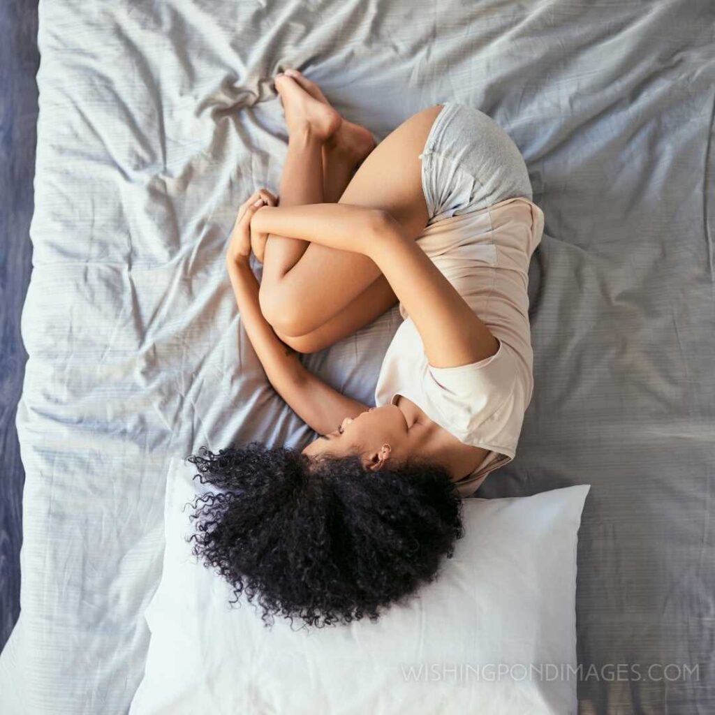 A young woman suffering from stomach cramps in her bedroom. Feeling alone images girl.