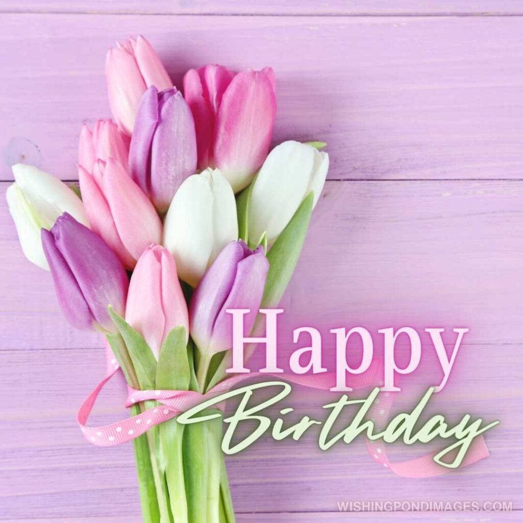 Bouquet of colorful tulips flowers on a pink wooden table background. Happy birthday tulips flowers images