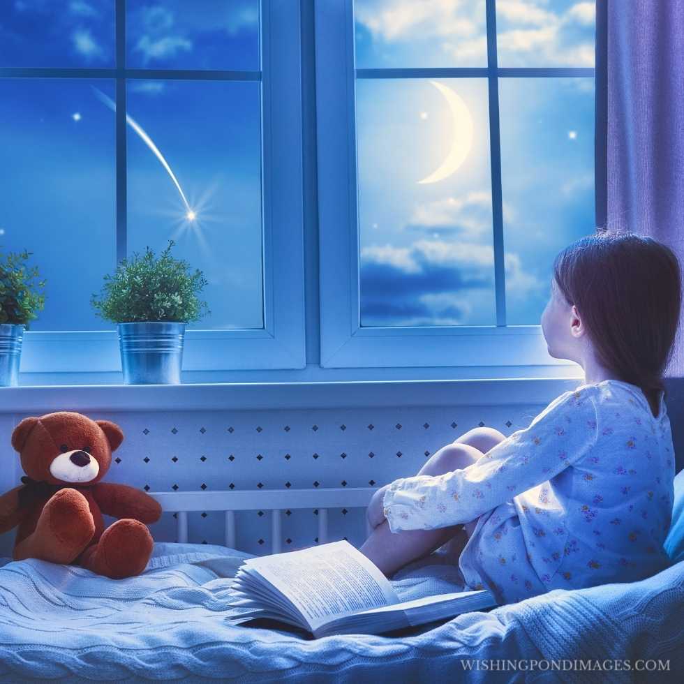 Cute child girl sitting at the window and looking at the stars. Sad girl in room.