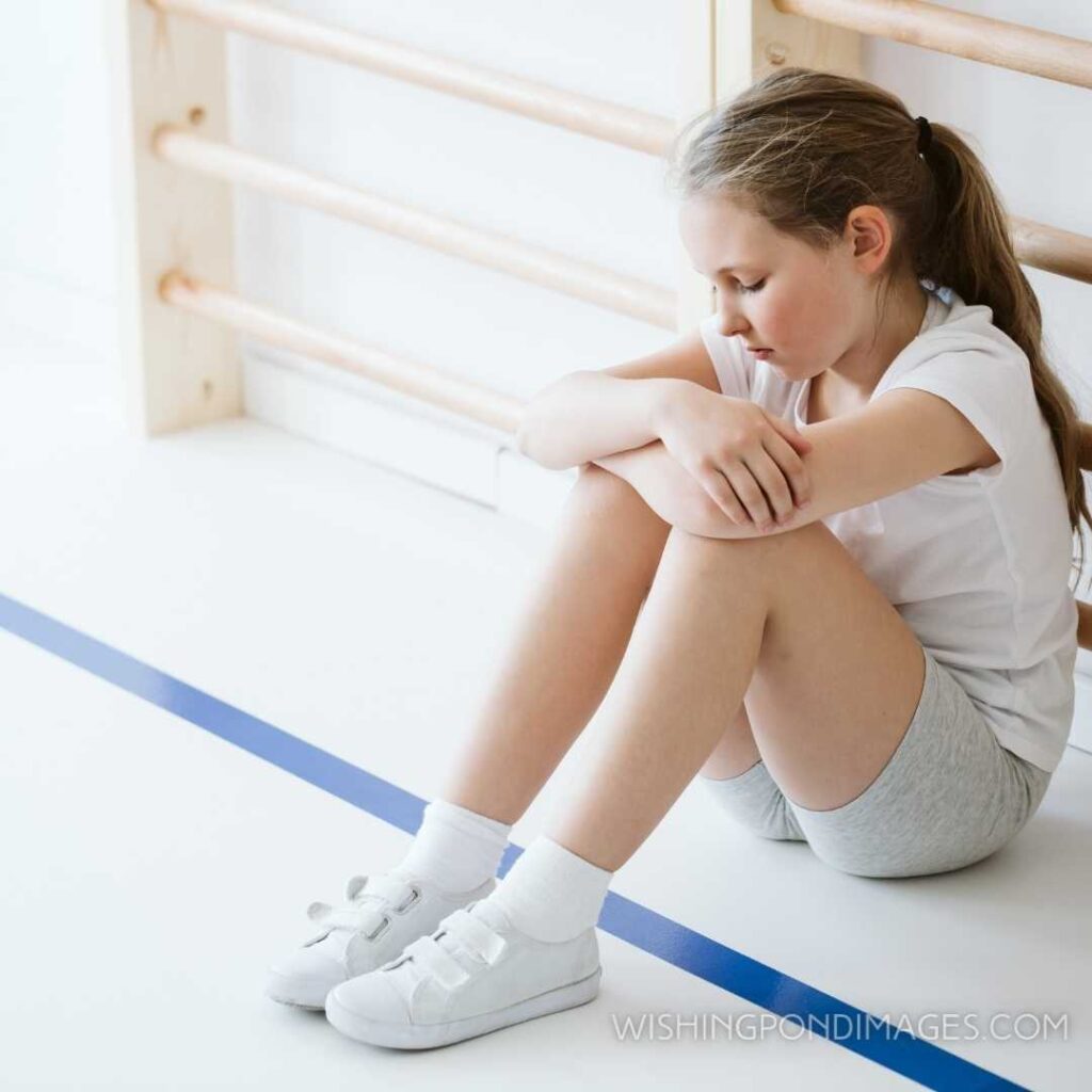 Demotivated girl sitting alone in a gym hall during classes. Feeling alone images girl.