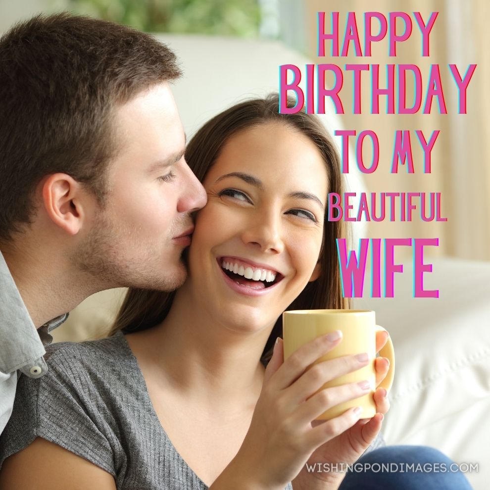 Happy husband kissing his wife in the living room at home. Happy birthday wife images.