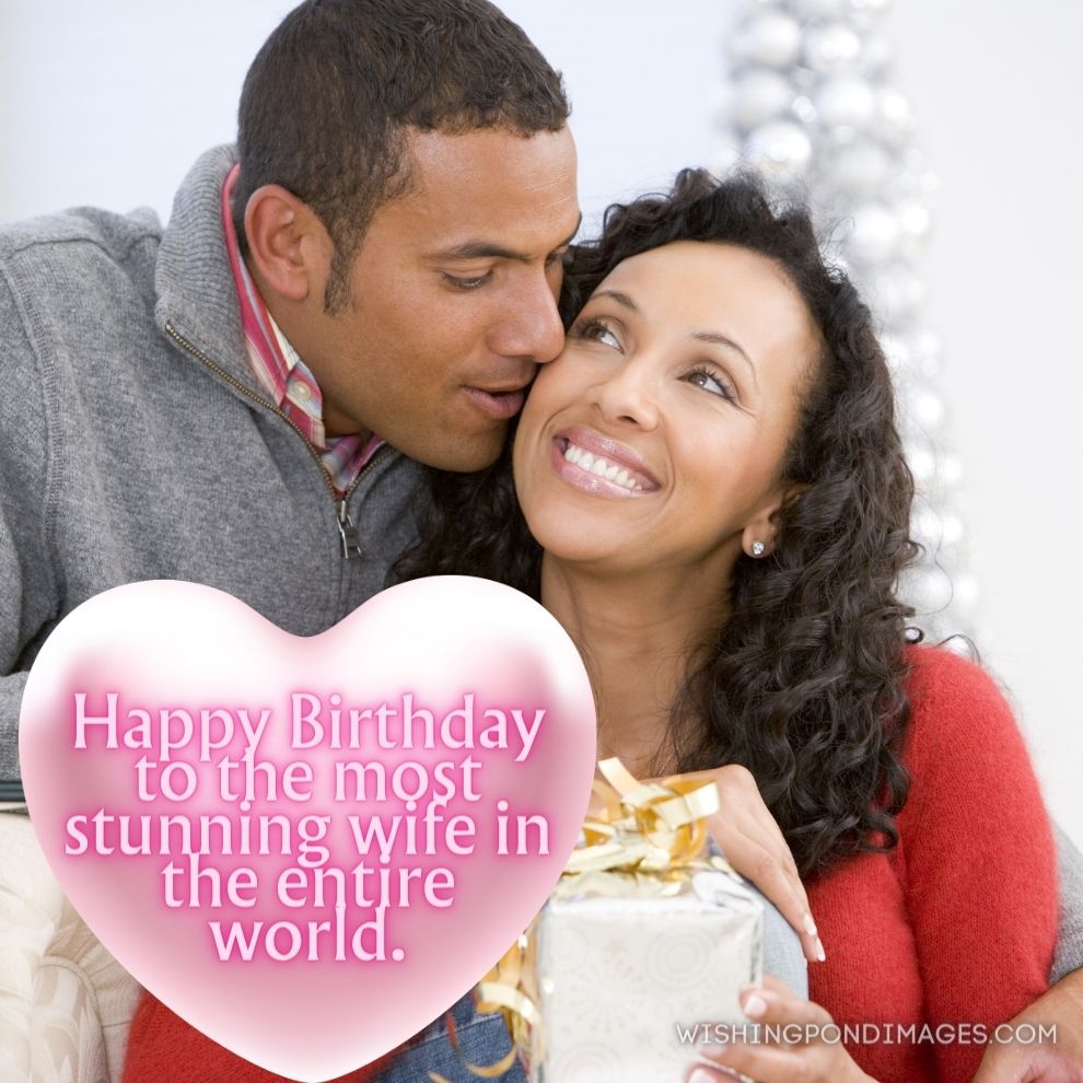 Husband and wife affectionately exchanging Christmas gifts in living room smiling. Happy birthday wife images.