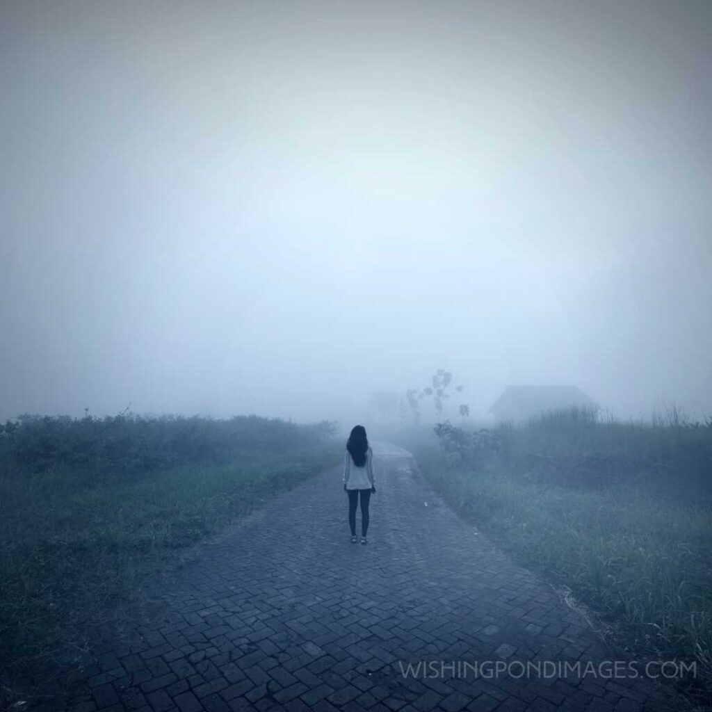 Rear view of a young woman standing alone on the path on a misty morning. Feeling alone images girl.