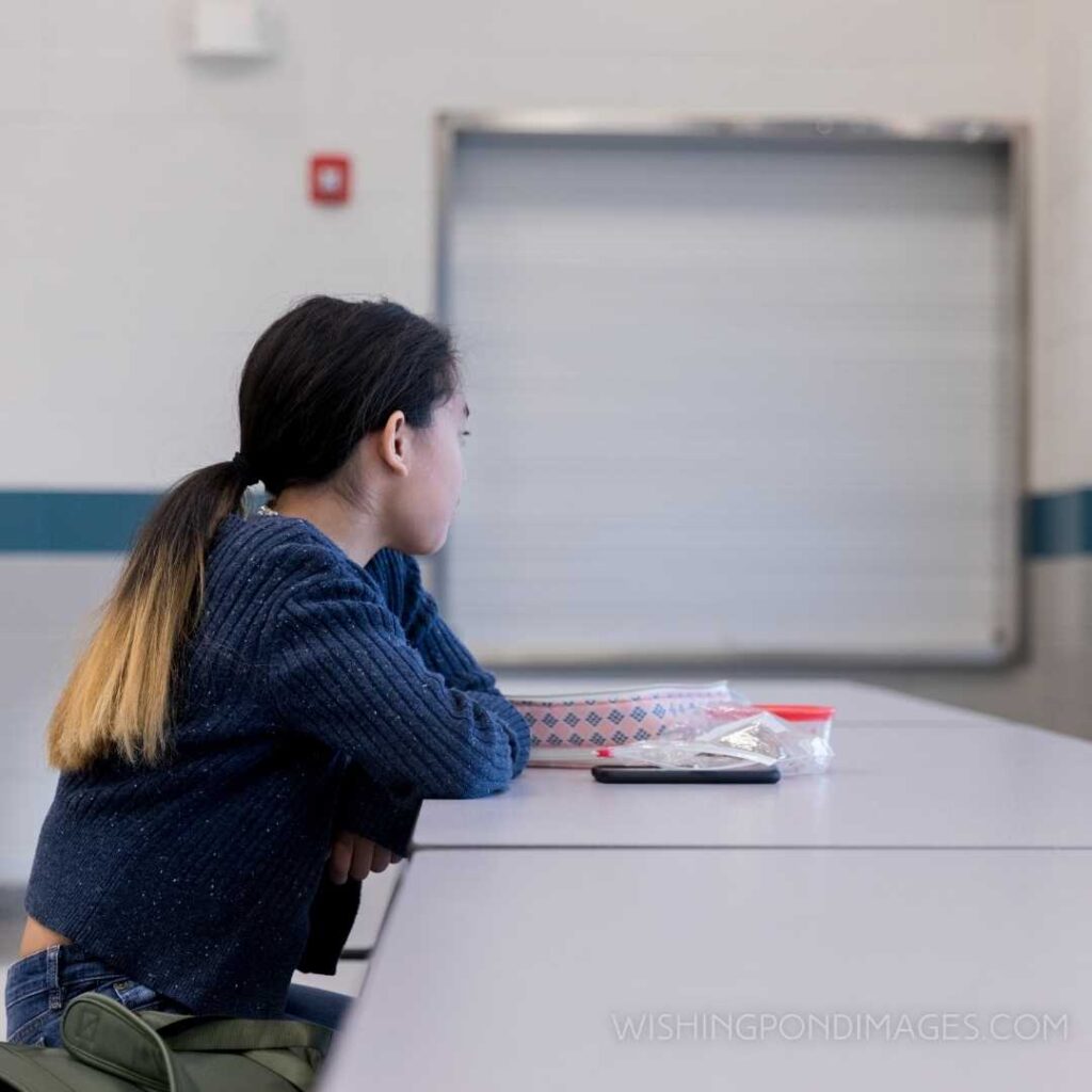 A sad preteen girl eats lunch alone in the school cafeteria. Feeling alone images girl