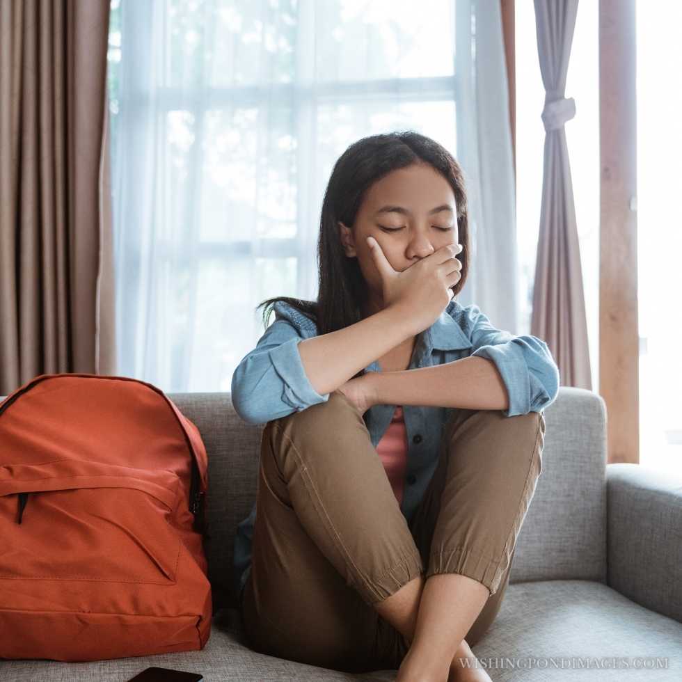 A sad teenager sitting on the couch by herself. Sad girl in room.