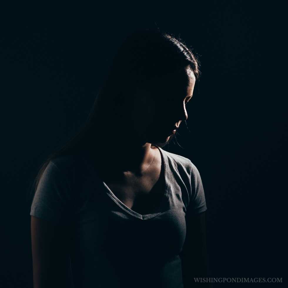 Sad woman in a dark room. Depression and anxiety disorder concept. Sad girl in room.