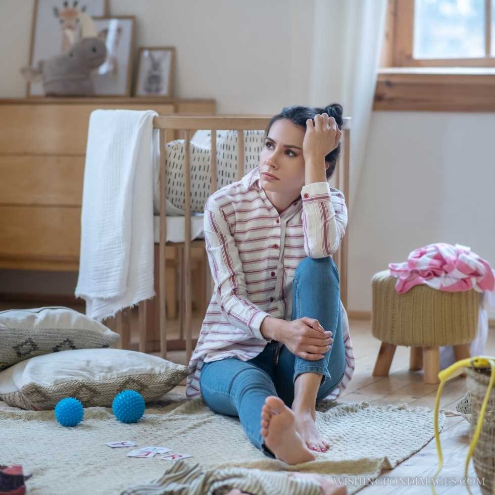 A tired woman sitting on the floor in a messy room, propping up her head. Sad girl in the room