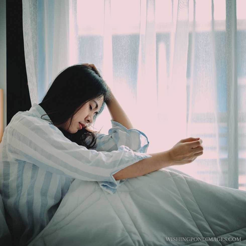 Unhappy Asian woman sitting on a bed looking sad and lonely. Sad girl in room