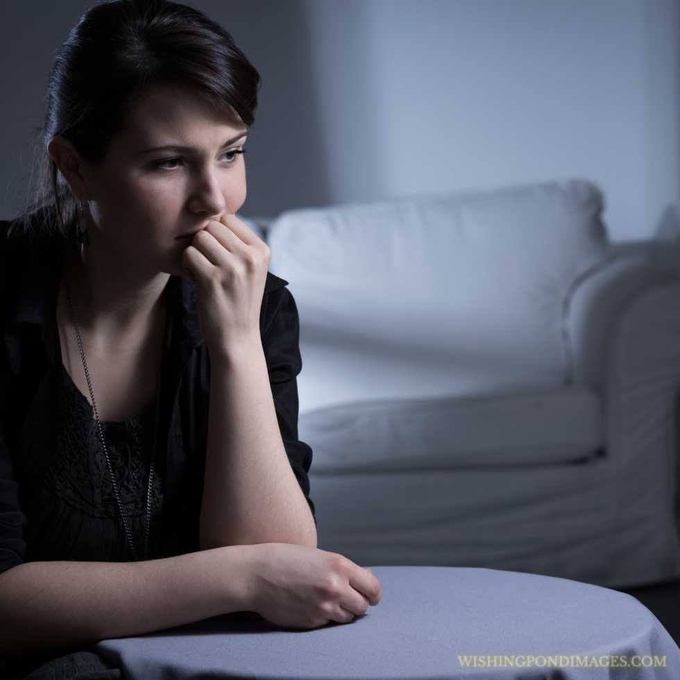 Young lonely sad woman sitting in an empty dark room. Sad girl in room.