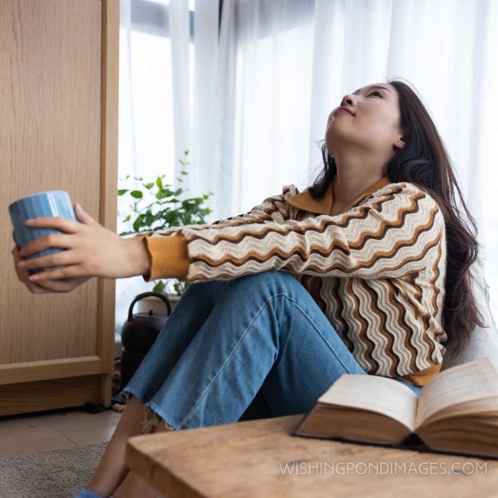 Young woman drinking a cup of coffee at home. Feeling alone images of girl