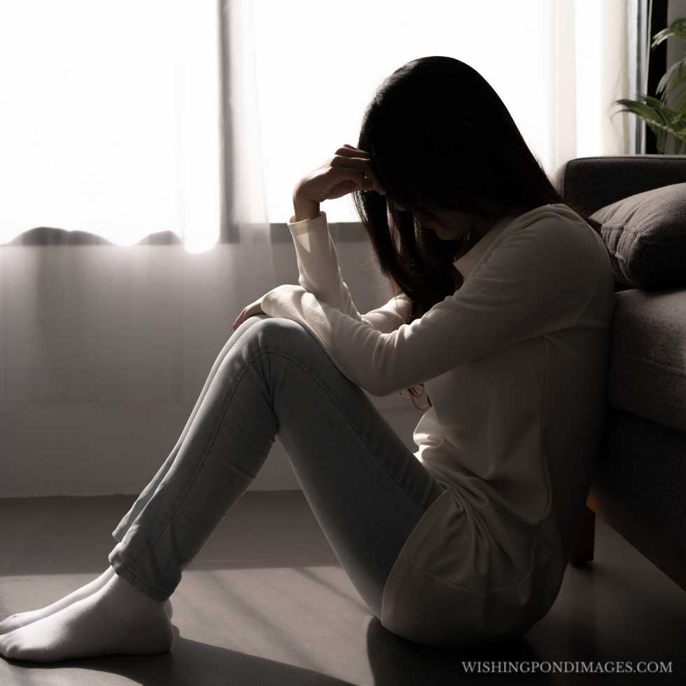 Young woman feeling depressed and stressed sitting in a dark bedroom. Sad girl in the room