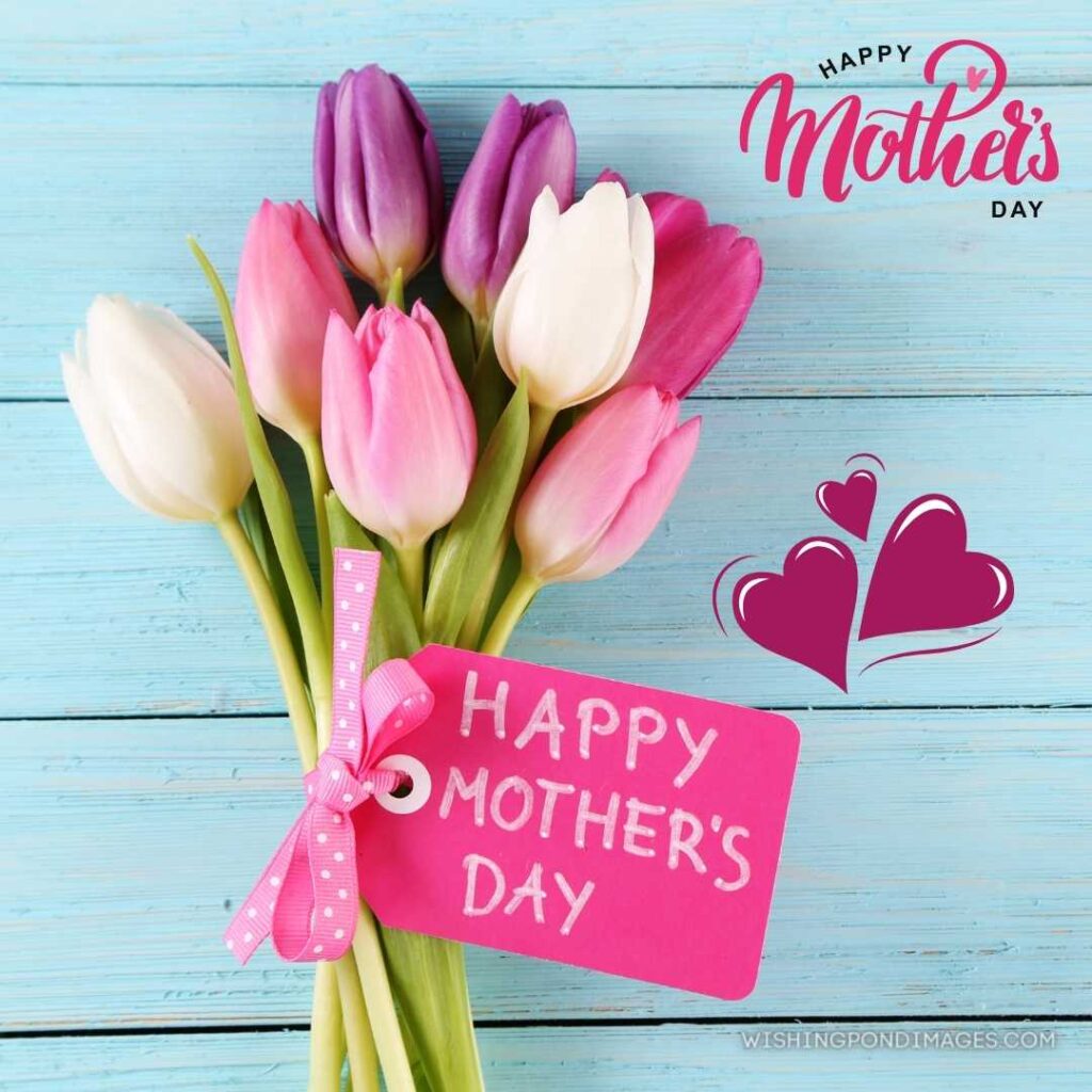 Beautiful tulips flowers bouquet with happy mother's day written on tag on sky blue wooden background. Happy Mothers Day images