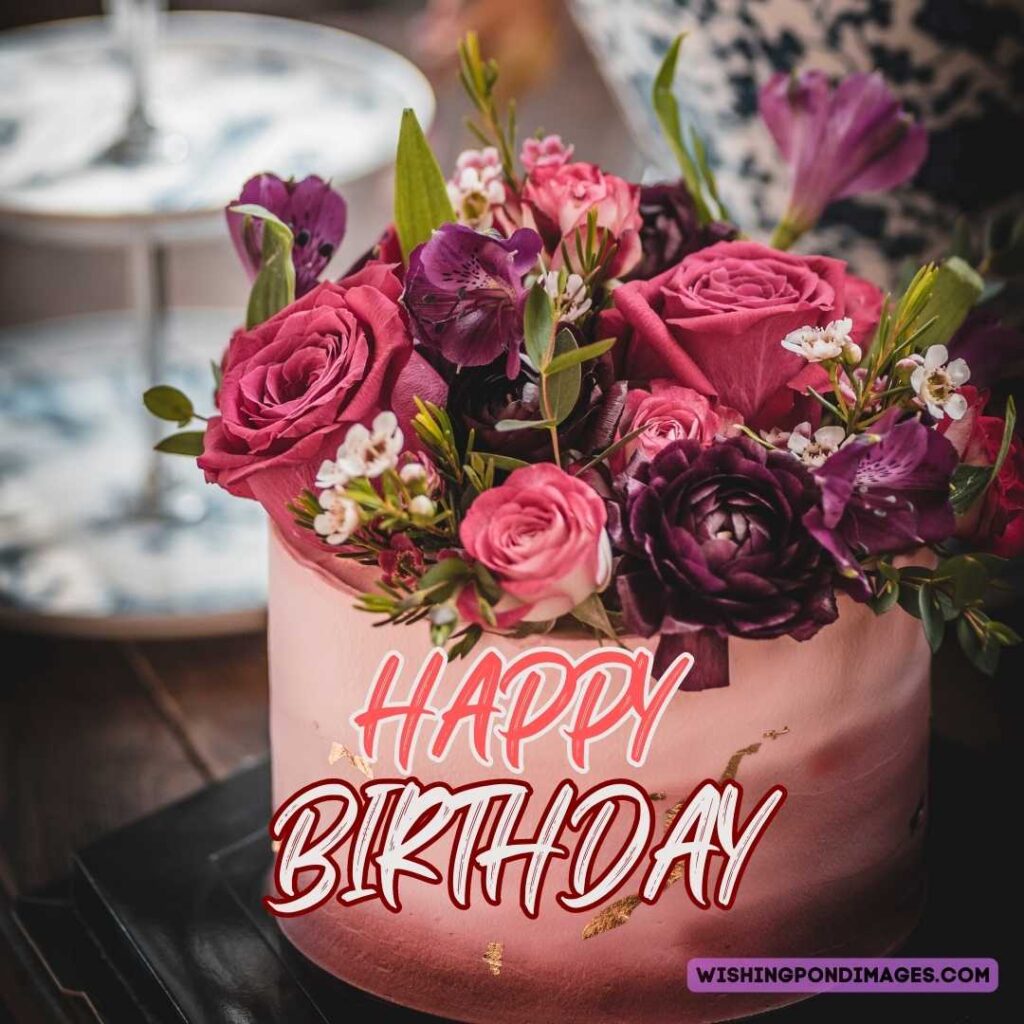 A peach colored beautiful cake with purple and pink flowers with leaves on top. Happy birthday cake flowers images