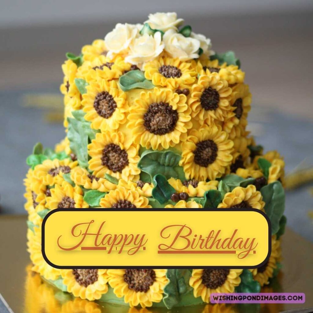 A two-layered sunflower flower cake sitting on the golden surface table. Happy birthday cake flowers images