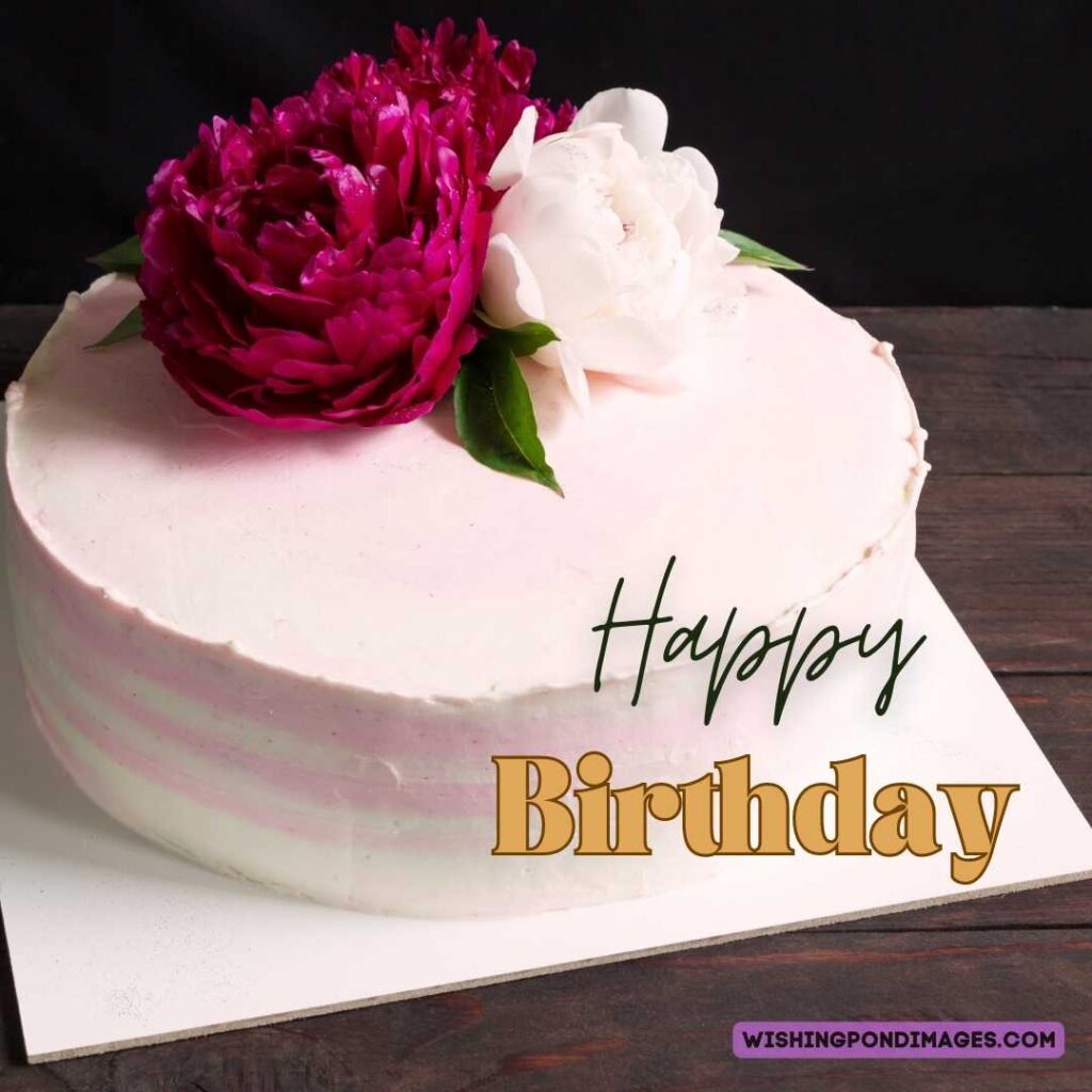 Light pink colored cake with flowers on top sitting on the wooden table. Happy birthday cake flowers images