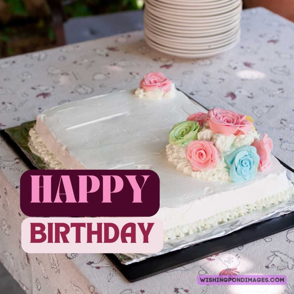 White color cake with colorful flowers sitting on the table. Happy birthday cake flower images